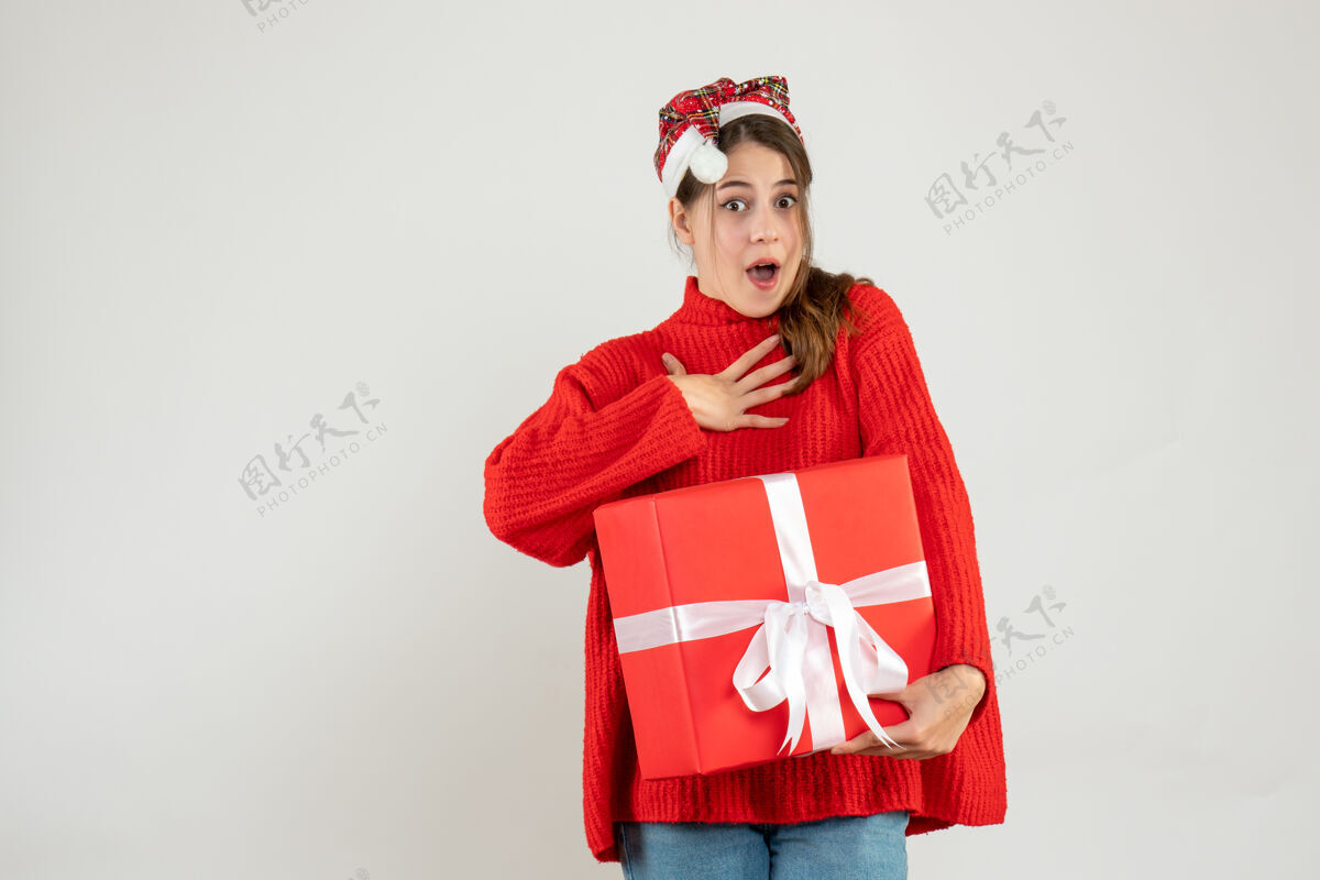 圣诞节一个戴着圣诞帽的女孩拿着一件白色的礼物圣诞老人女孩举行