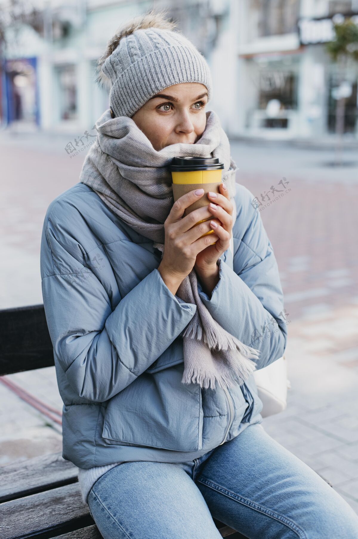 季节穿着冬衣的年轻女子手里拿着一杯咖啡咖啡杯子户外
