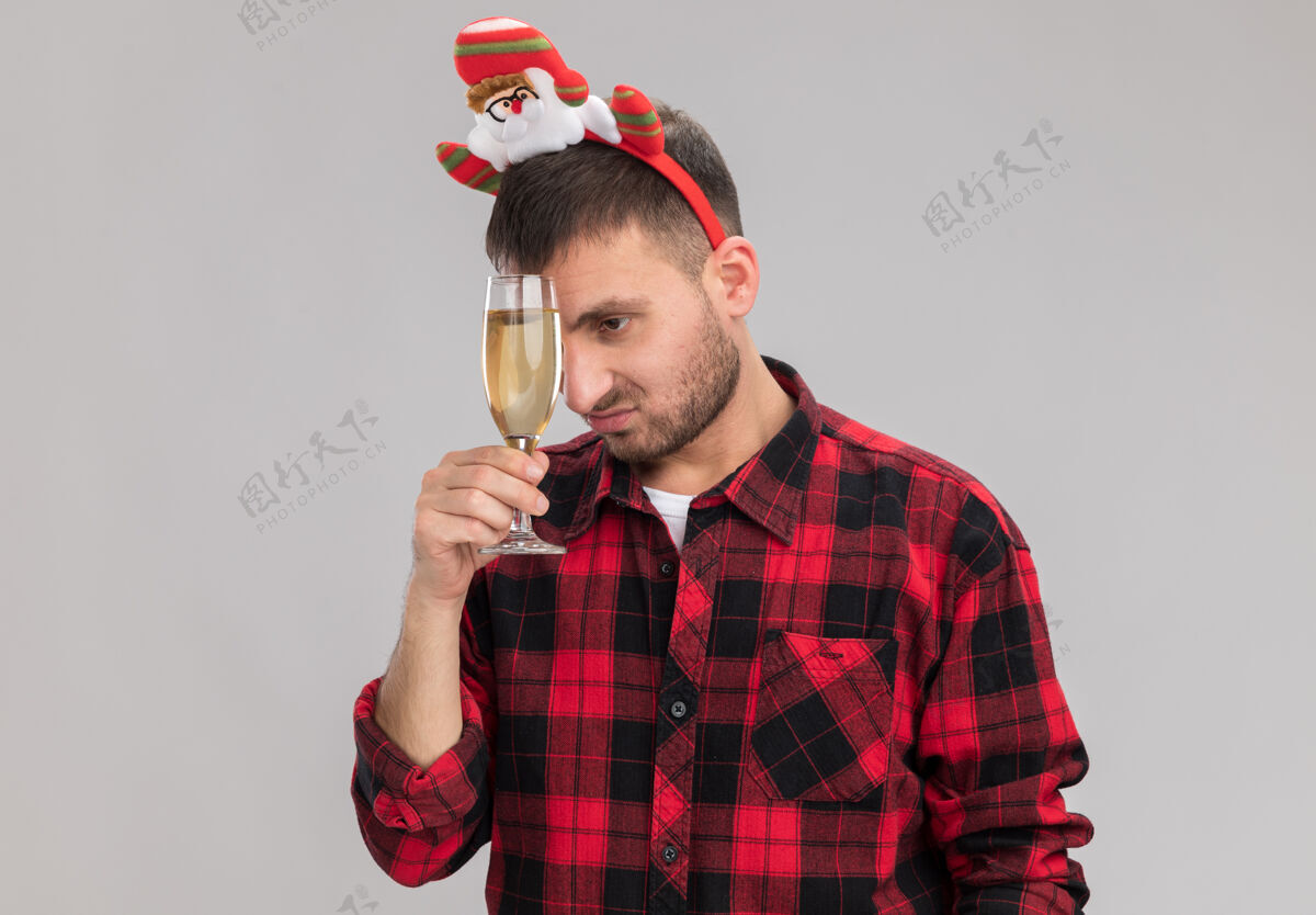 侧悲伤的白人年轻人戴着圣诞头带 拿着一杯香槟 用它抚摸着额头 看着隔离在白色背景上的一边 留着复印空间额头触摸悲伤