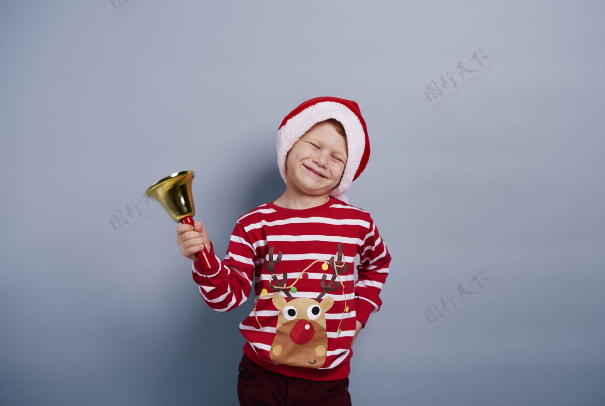 颤抖带着手铃的快乐男孩在摄影棚拍摄幽默圣诞庆祝