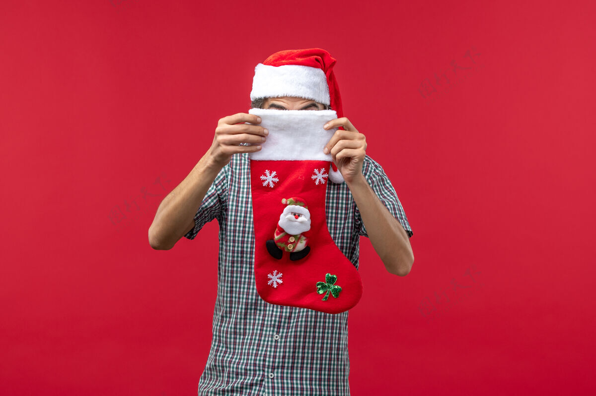 服装红墙上穿着圣诞袜的年轻人的正视图身材年轻人礼物