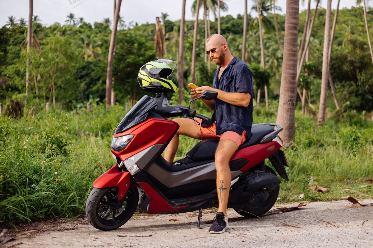 运动在热带丛林的田野上纹着红色摩托车的壮汉滑板车人自由
