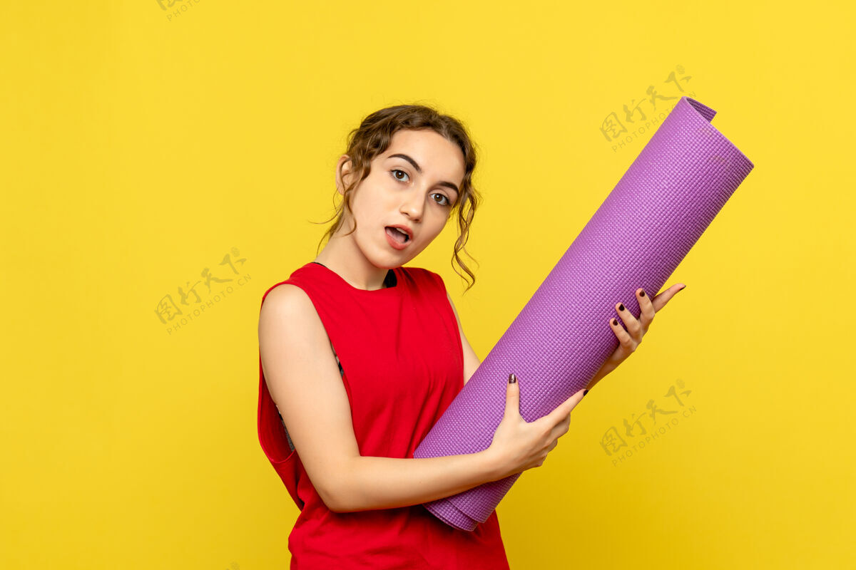 地毯黄墙上紫色地毯的年轻女子的正视图成人女性生活方式
