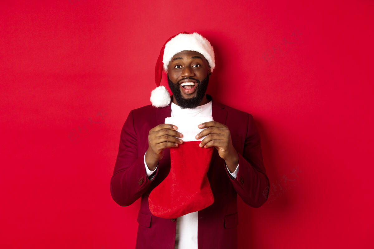 英俊兴奋的黑人打开圣诞袜子与礼物和糖果圣诞老人模特快乐