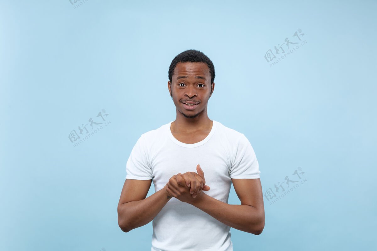 人穿着白衬衫的年轻非洲裔美国男模的特写肖像看起来很开心 很吸引人 微笑着男人顺序手势