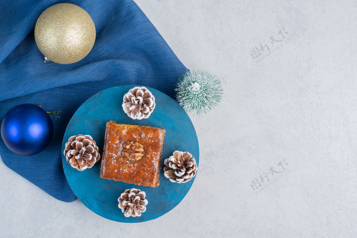 装饰性的圣诞饰品和一个树雕像旁边bakhlava和两个松果在一个蓝色的大理石板表面美味糖美味的