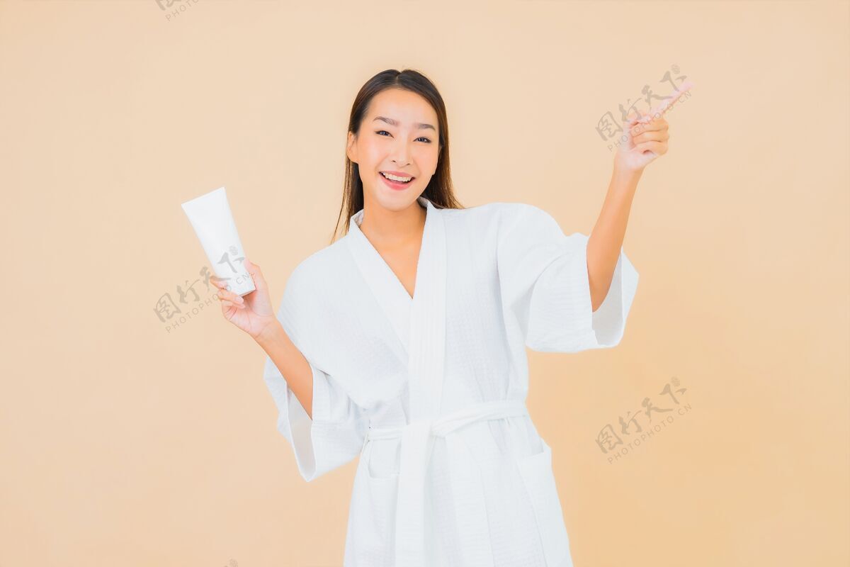 肖像肖像美丽的亚洲年轻女子与瓶乳液和面霜米色可爱模特卫生
