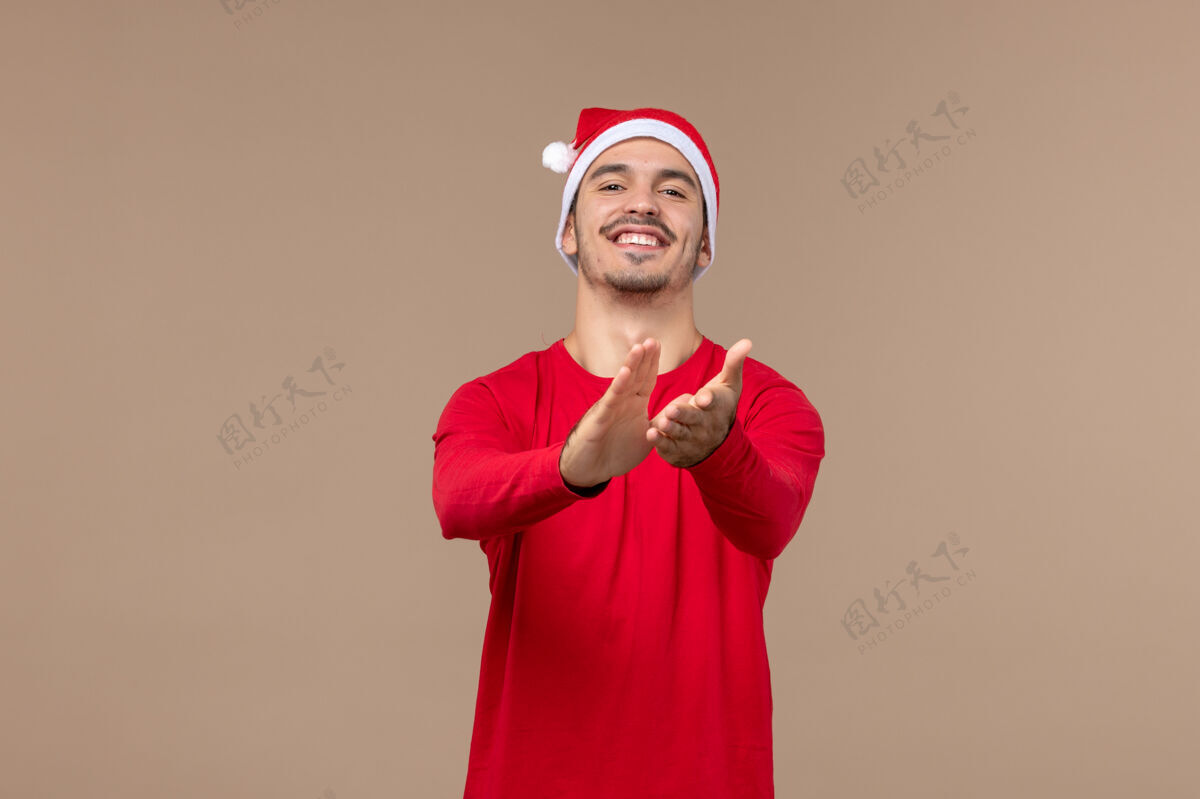 圣诞节正面图棕色办公桌上的年轻男性带着兴奋的表情圣诞节情感假期人快乐年轻