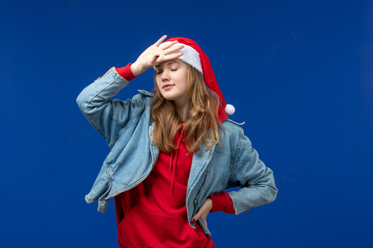 肖像前视图：年轻女性 蓝色背景 红色圣诞帽 圣诞情感色彩模特风景快乐