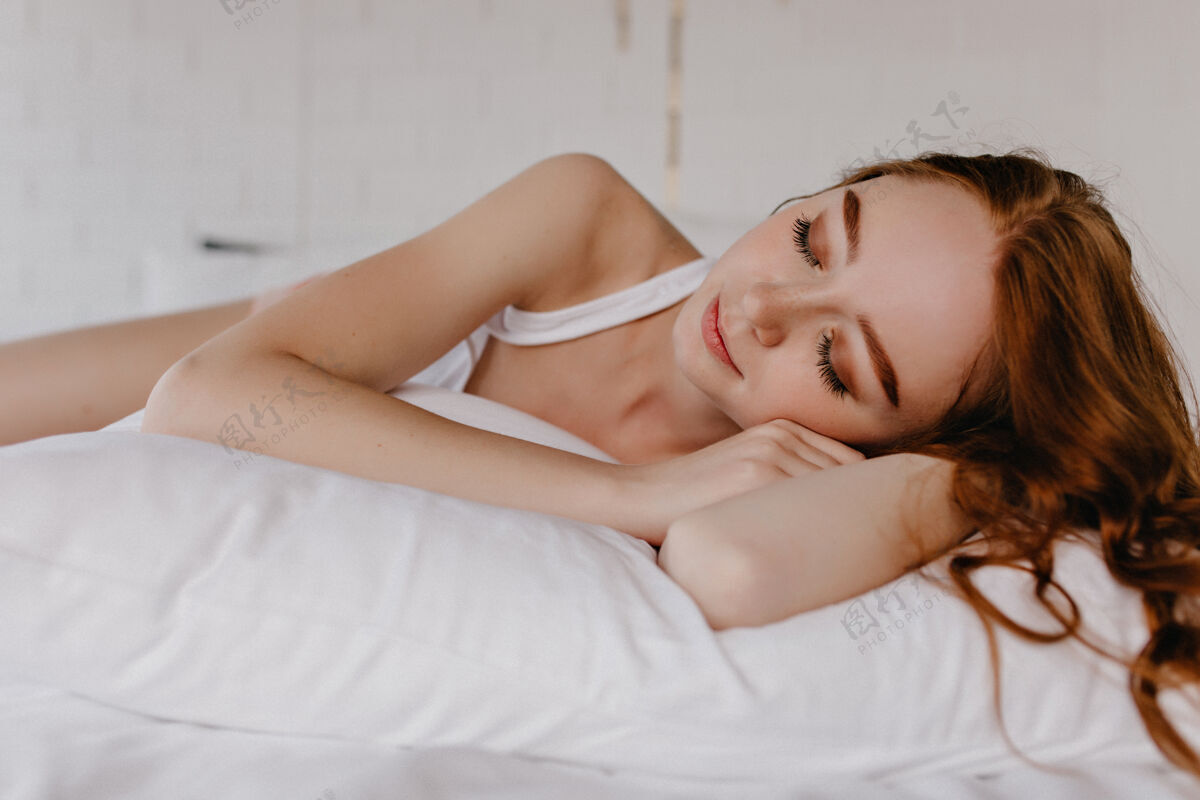可爱可爱的女孩 波浪形的发型睡在枕头上室内照片疲惫的姜女模特化妆人放松享受