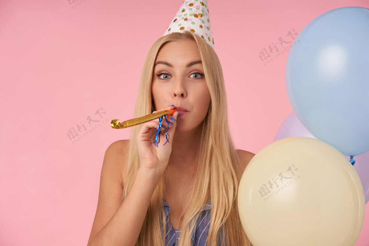 年轻室内照片的积极长发金发女性庆祝节日与党的服装 与粉红色背景上的五彩气球摆姿势人 娱乐和节日属性漂亮室内节日