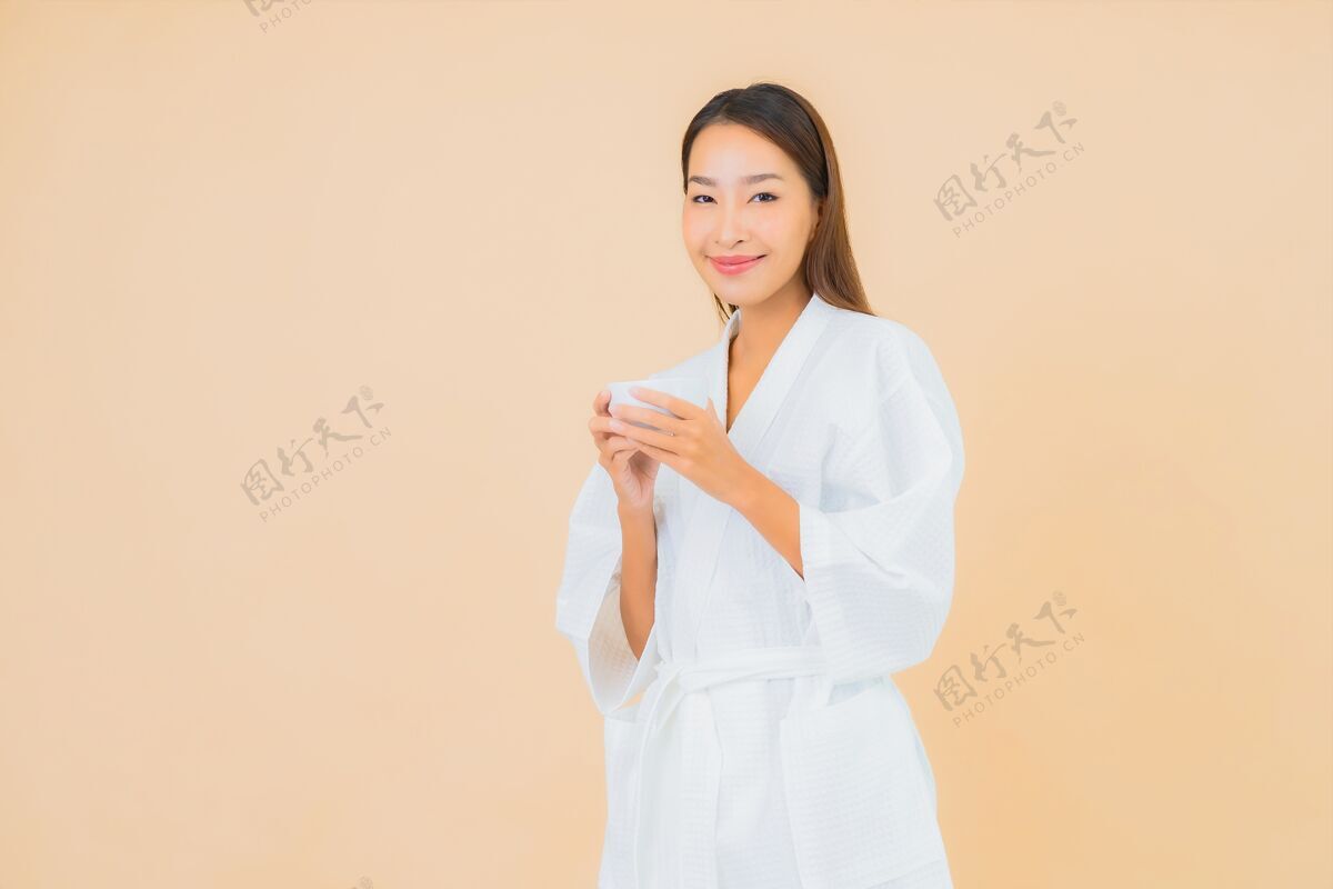 友好肖像美丽的亚洲年轻女子与咖啡杯米色休闲饮料休息