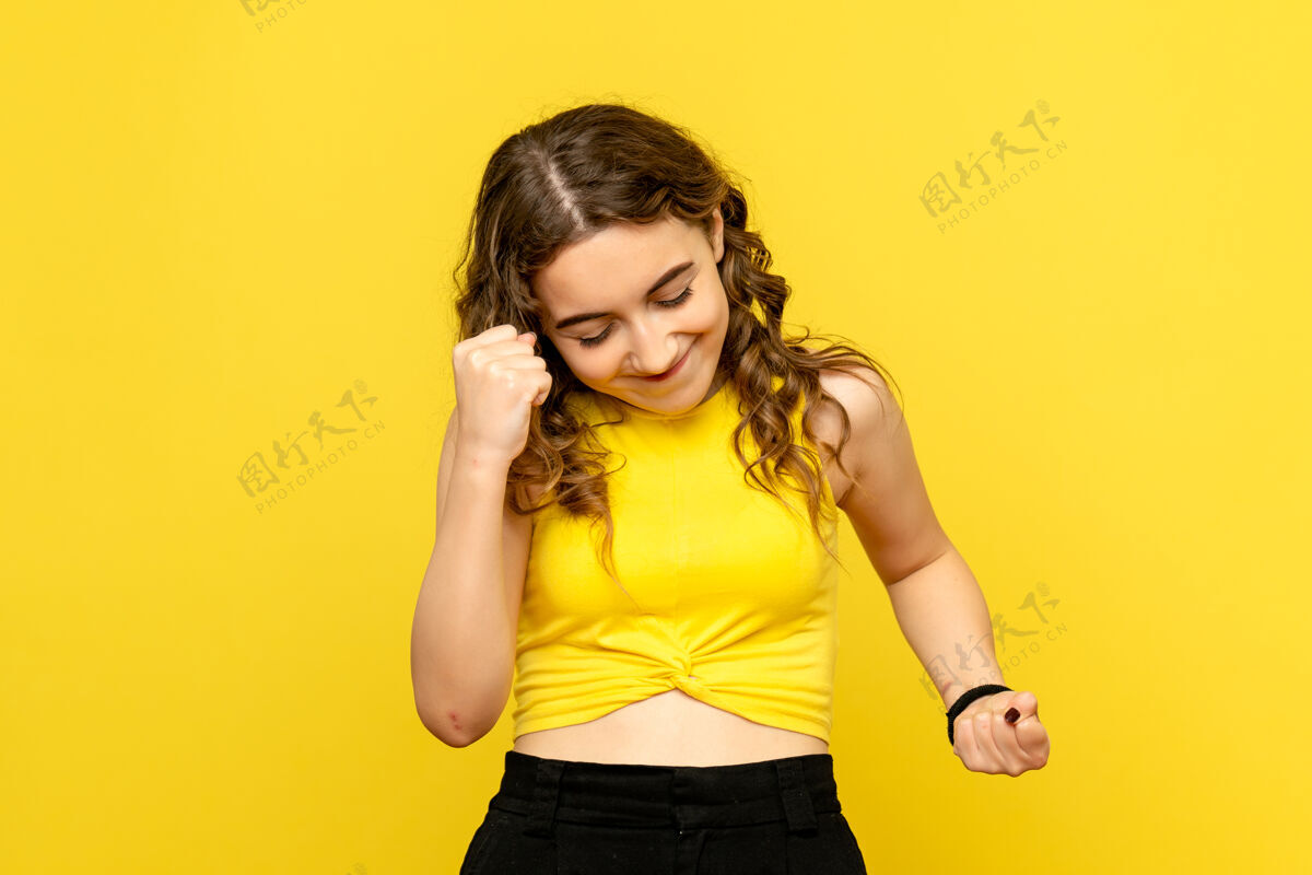 正面年轻女子在黄墙上欢庆的正面图女性漂亮年轻女性