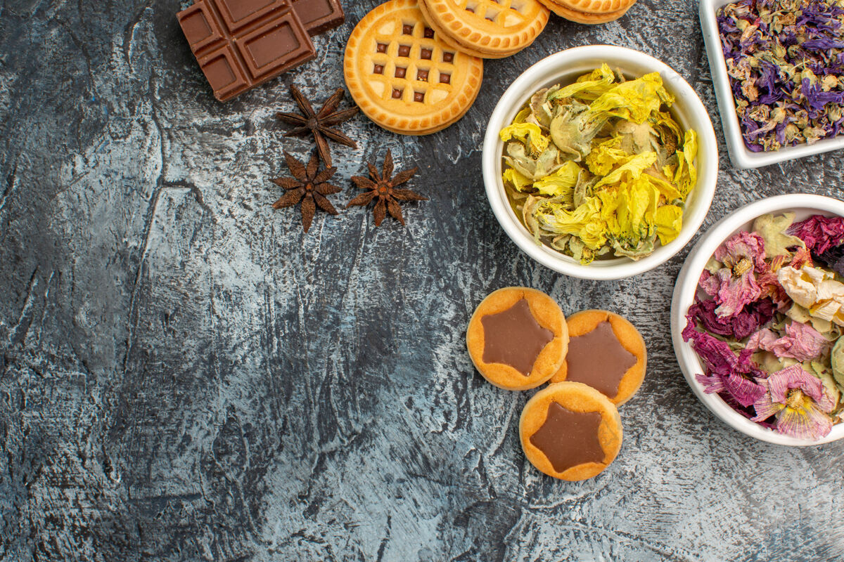 茴香饼干和碗干花和巧克力棒与八角在灰色的地面上顶部食物视图