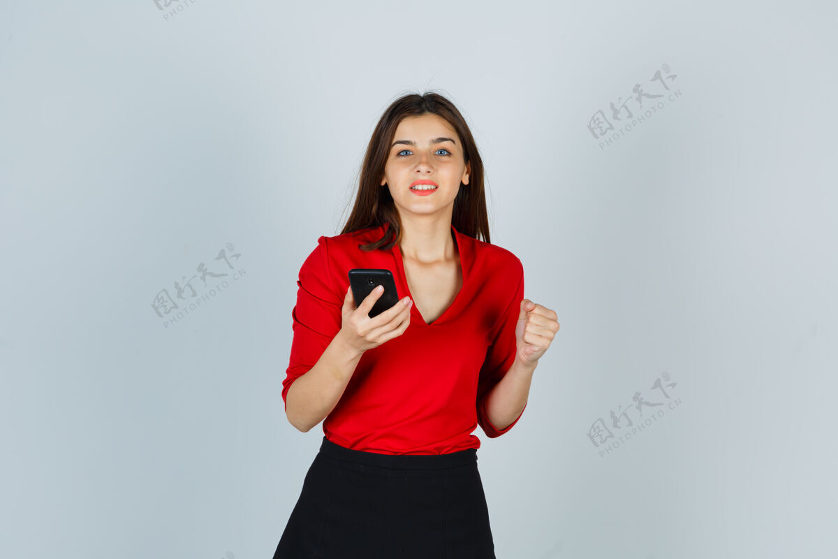 自然一位年轻女士手持手机 穿着红色上衣展示获奖者的姿态人抱着肖像