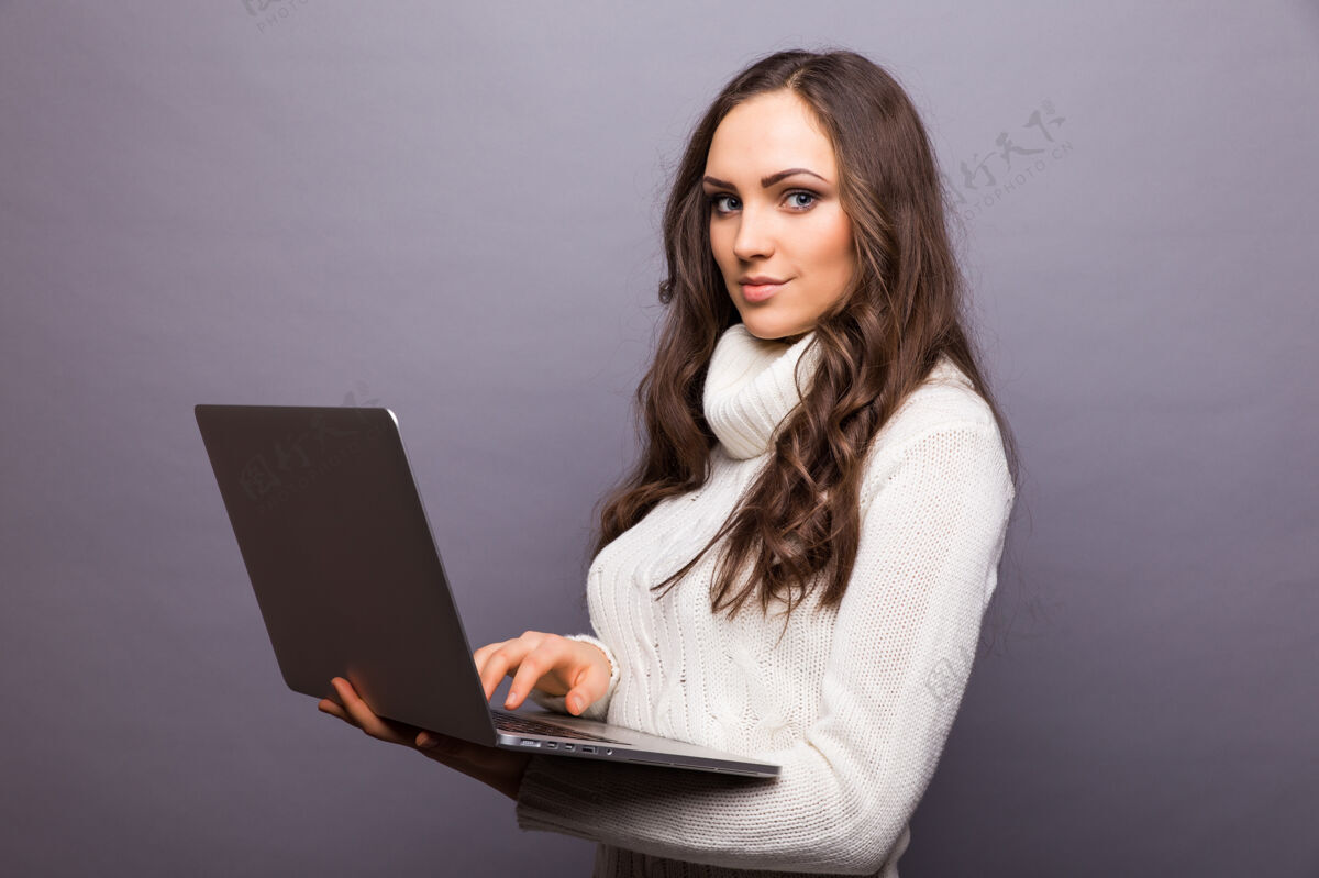 连接一个快乐的惊讶的女人站在灰色的墙上 笔记本电脑被隔离无线女人社交