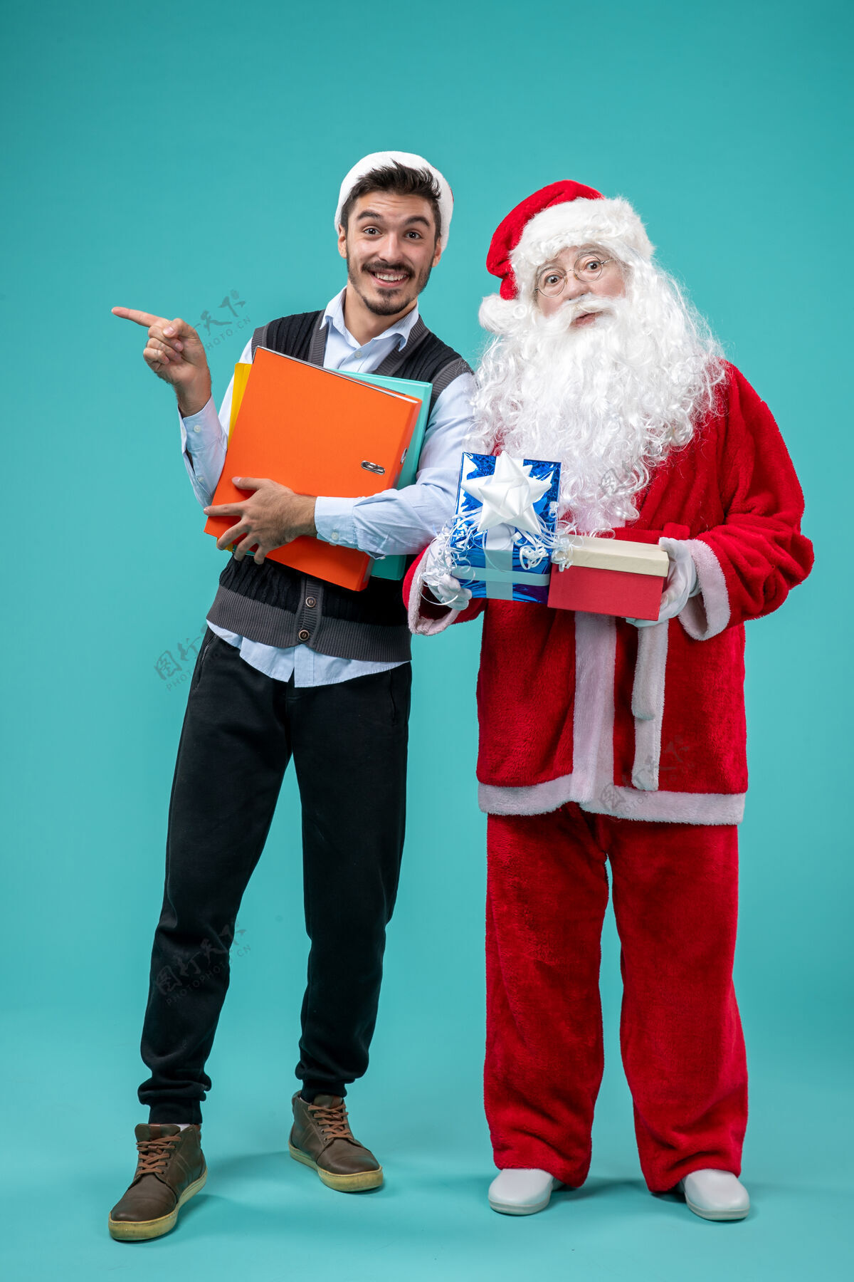 成人圣诞老人与年轻男性和礼物在蓝色墙上的正面视图快乐庆祝男性