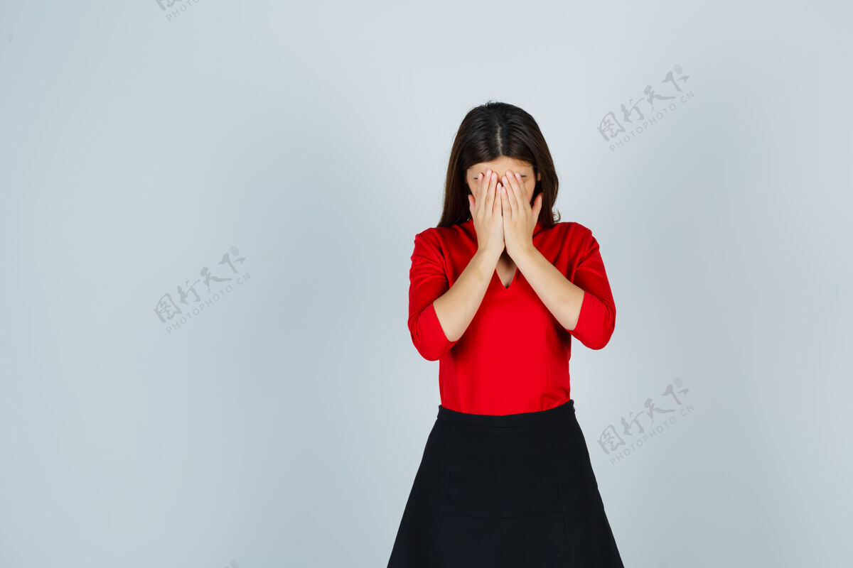 掩护一个穿着红衬衫 黑裙子 手捂着脸的年轻女人 看上去很惭愧隐藏快乐羞耻
