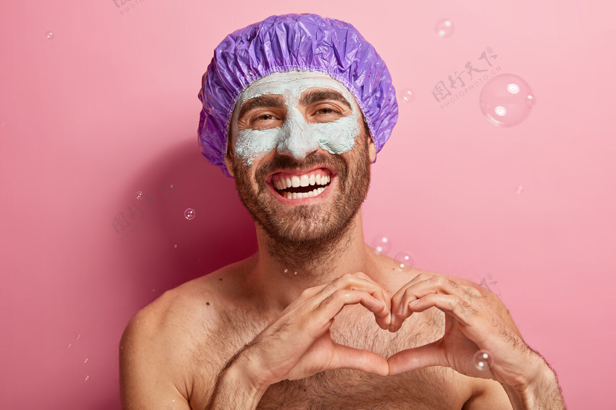 手势笑容可掬的快乐男人的画像 喜欢洗衣服和美容 脸上戴着泥面具 赤裸上身站着手势高兴放松