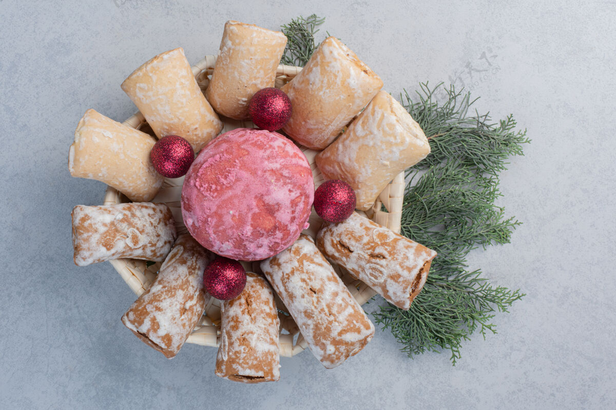 松树圣诞饰品和饼干捆在一堆松枝上的白色篮子里曲奇包装甜的