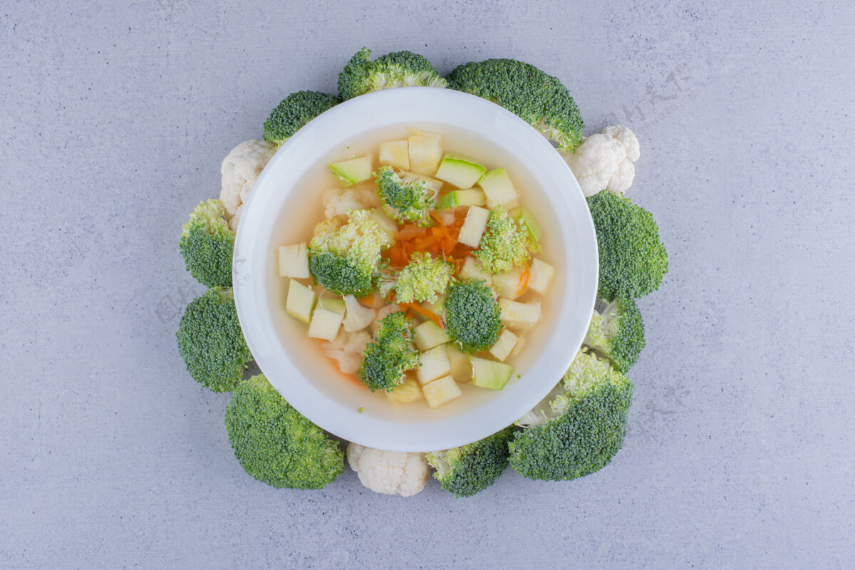 美味花椰菜和花椰菜汤放在一个碗里 在大理石背景上用花椰菜圈起来碗汤西兰花