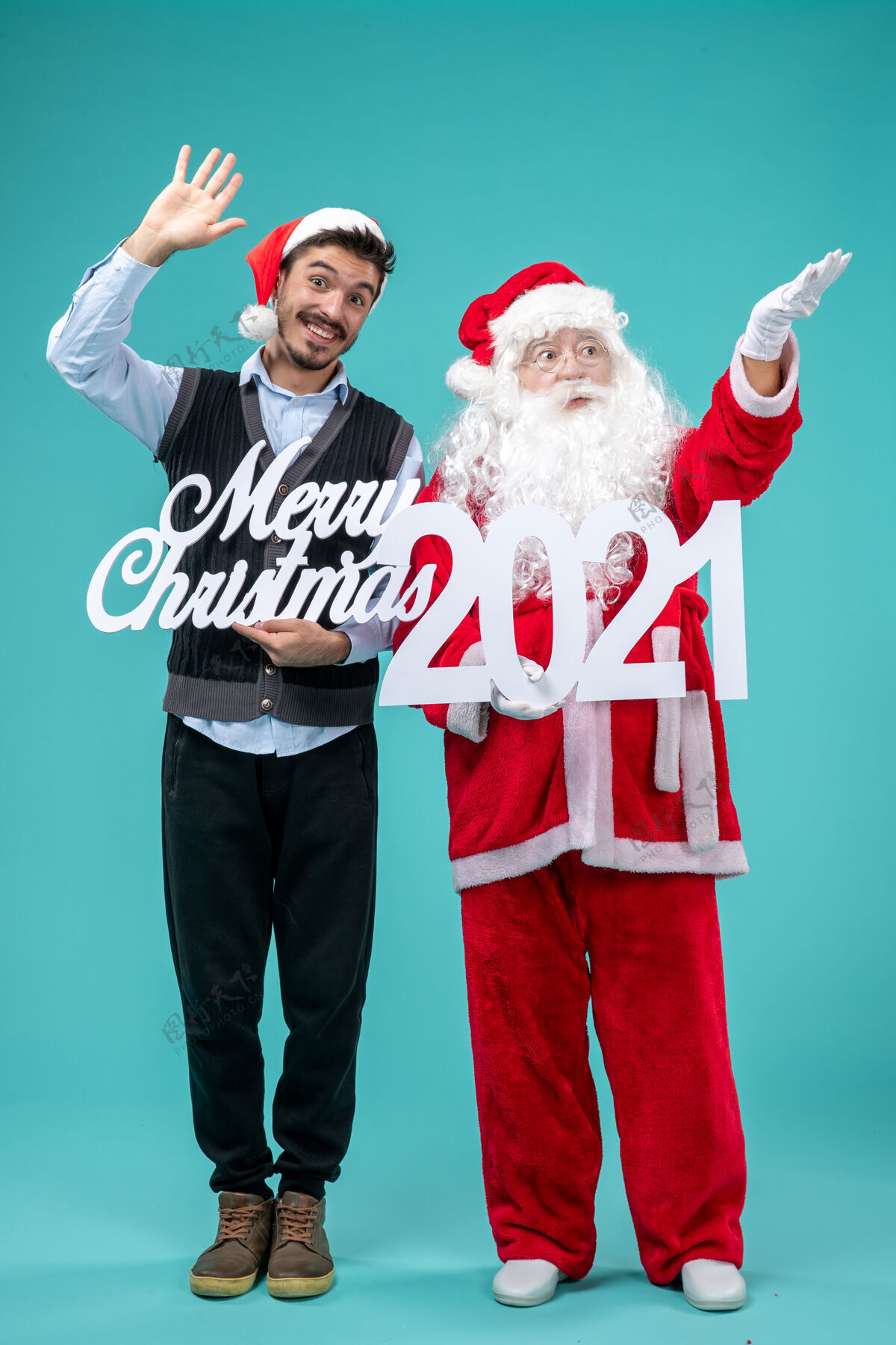 快乐前视图圣诞老人与年轻的男性举行圣诞快乐和蓝色背景上的作品男前支持者