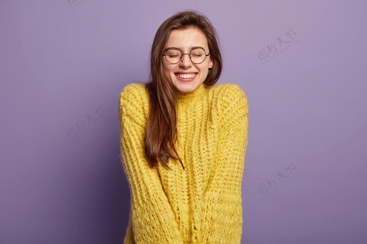 高兴《快乐女人的孤立画像》有着牙齿般的微笑 闭上眼睛 从赞美中感受到快乐 戴着眼镜和黄色套头衫 站在紫色的墙上积极的情绪和感觉概念表情白种人积极