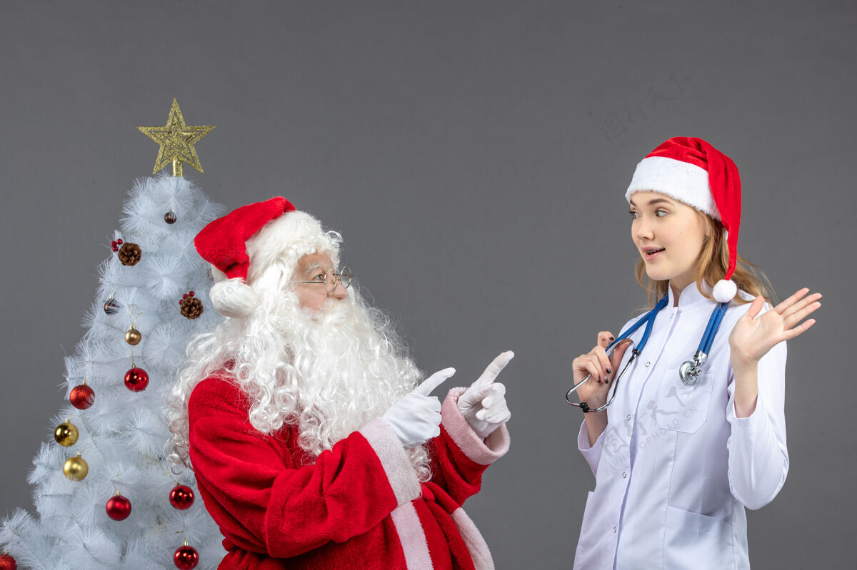 医院圣诞老人和年轻女医生在灰色墙上的正视图节日圣诞正面
