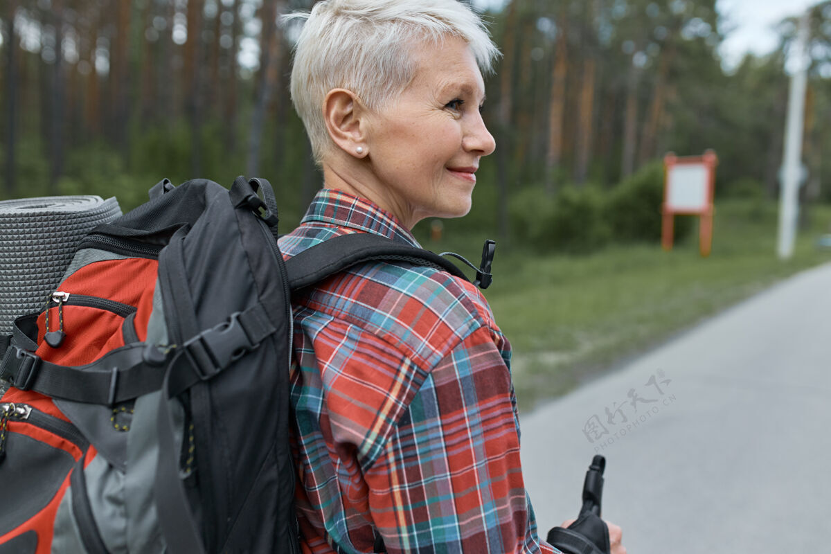 远足者后景：中年妇女 披着小精灵的发型 背着背包 徒步旅行 去山里度周末独自远足运动