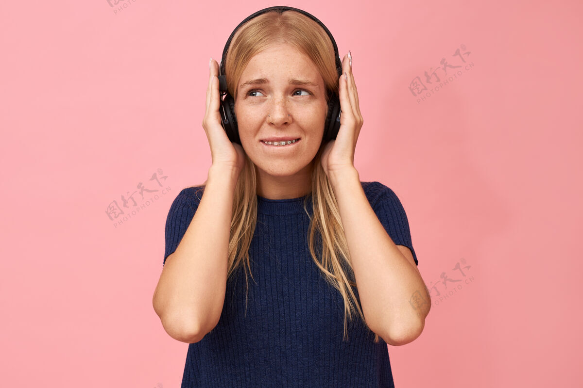脸庞一个可爱的少女手放在耳朵上 用无线耳机在mp3播放器中欣赏高品质音乐的孤立镜头无线模特女性
