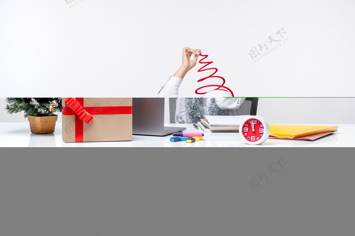 圣诞节正面图：年轻的女工坐在她工作的地方前面 背景是白色的办公室坐着工作