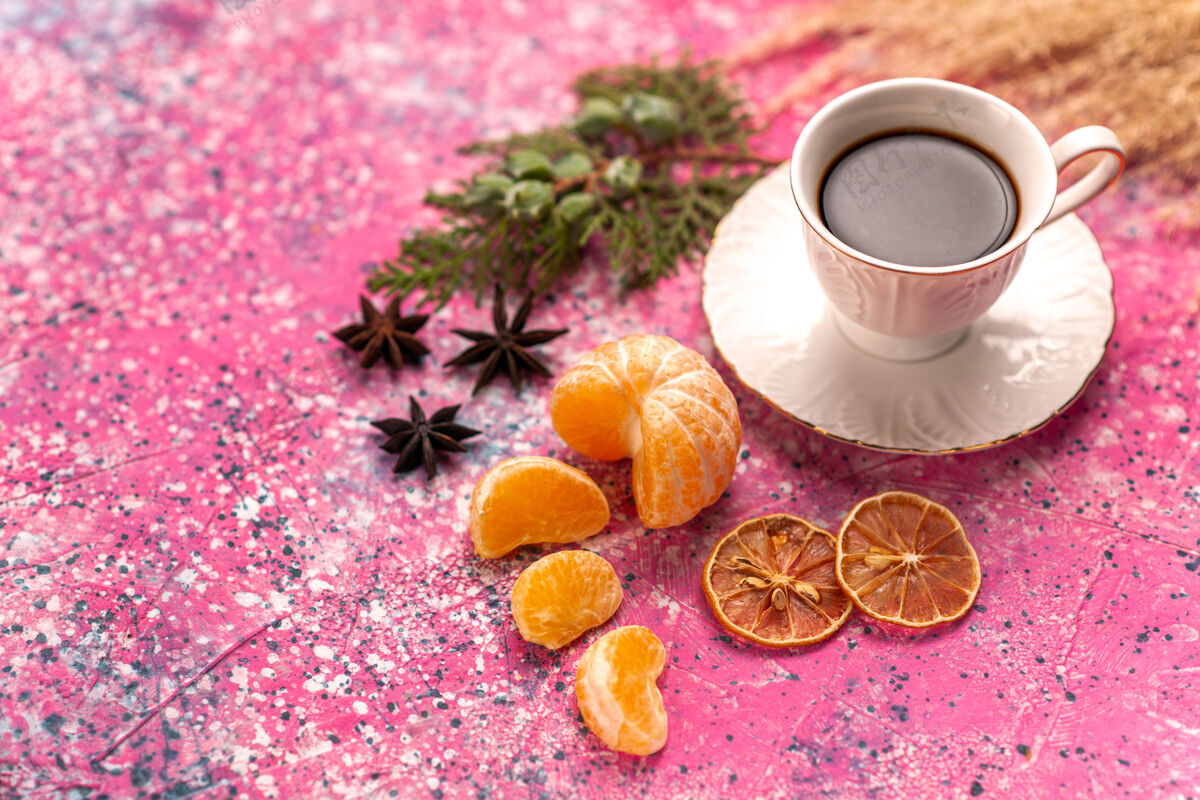 关闭半顶近景茶杯 浅粉色桌上放着橘子柑橘甜味花