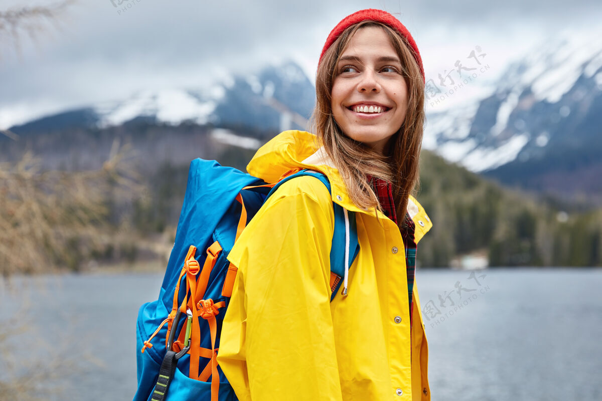 满意乐观的欧洲女游客横观一边高高兴兴地看 一边享受走在山湖边 欣赏美丽的风景人们装备悬崖包