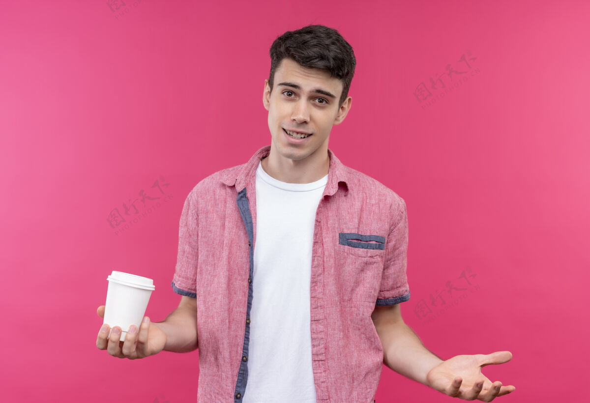 咖啡微笑的白人年轻人穿着粉色衬衫 手里拿着一杯咖啡 在孤立的粉色背景上举手小伙子手年轻人