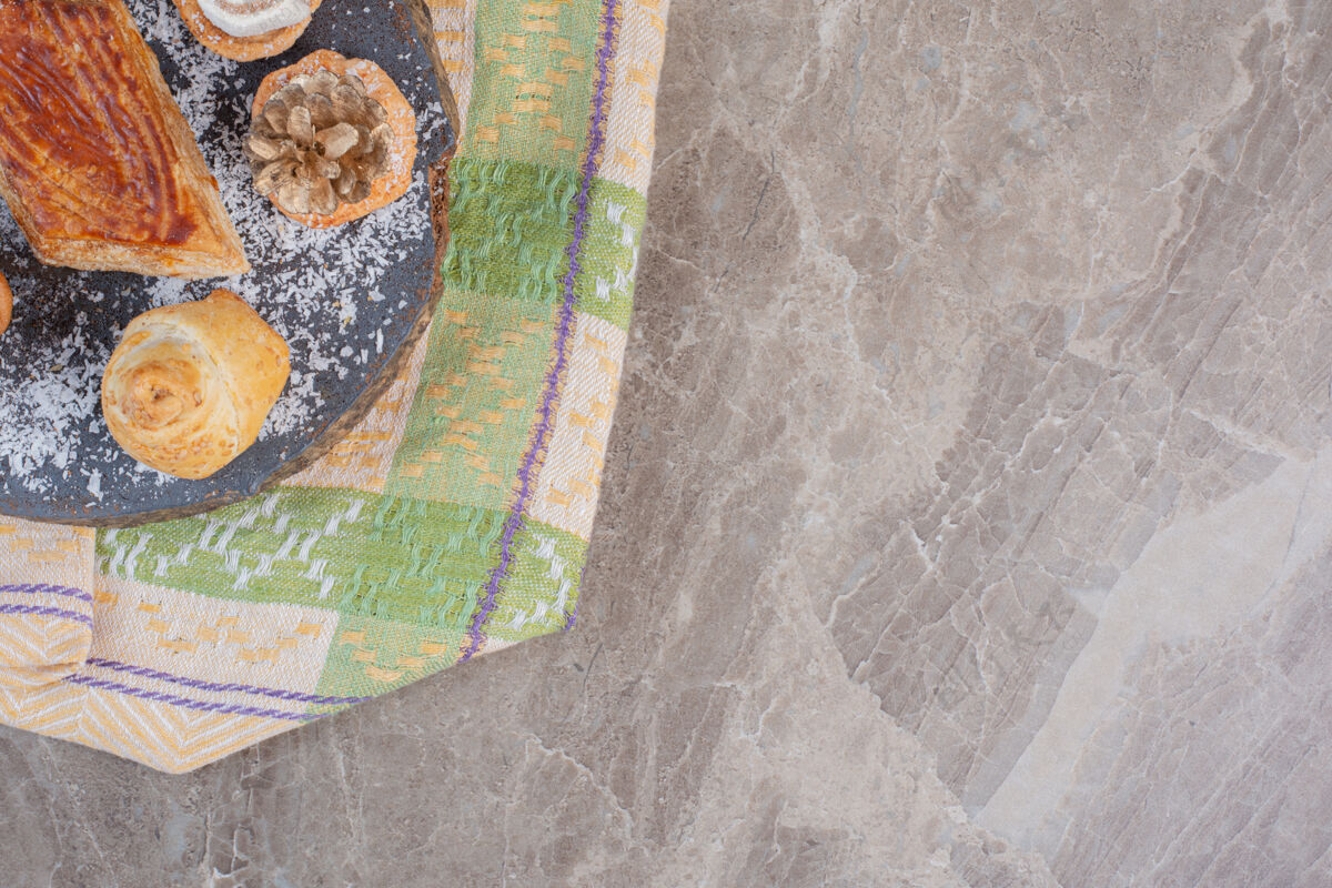 糕点美味的kyata周围有饼干 上面放着木棉花和松果 放在大理石板上桌布美味板