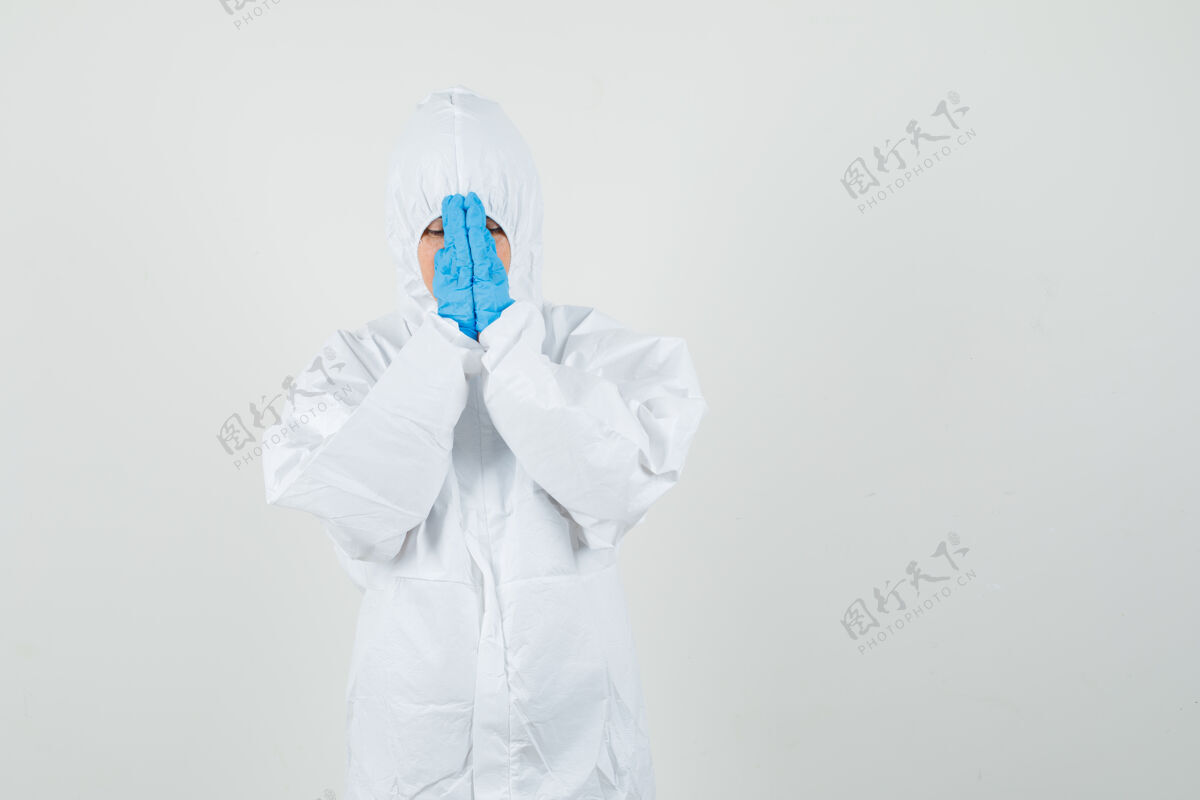 护理穿着防护服的女医生手牵手祈祷诊所医学肖像