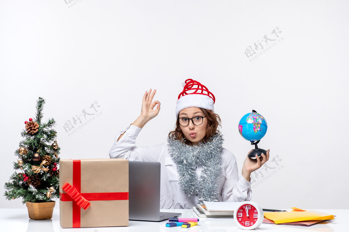 办公室正面图：年轻的女工坐在她拿地球仪的地方前面 背景是白色的白色坐着风景