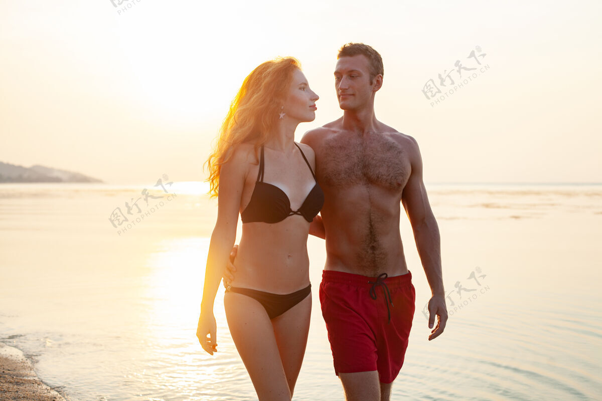 蜜月年轻性感浪漫的情侣在夏天的沙滩上快乐地穿着泳装玩情侣人乐趣