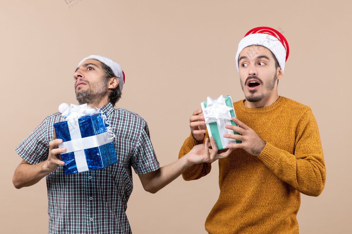 伙计们前视图两个困惑的家伙试图改变他们的圣诞礼物米色孤立的背景两个看法前面