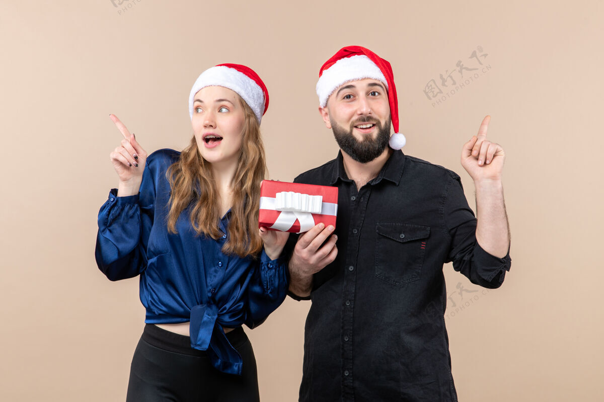 人一个年轻女人和一个男人在粉红色的墙上给她礼物的前视图快乐礼物圣诞节