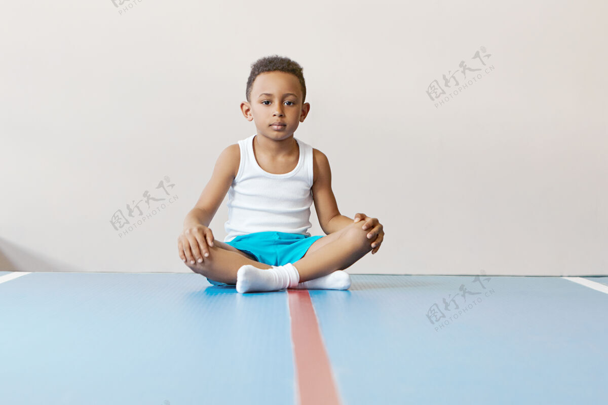 冥想室内形象的自我决定英俊的非洲男孩穿着运动服保持双腿交叉力量坐着放松