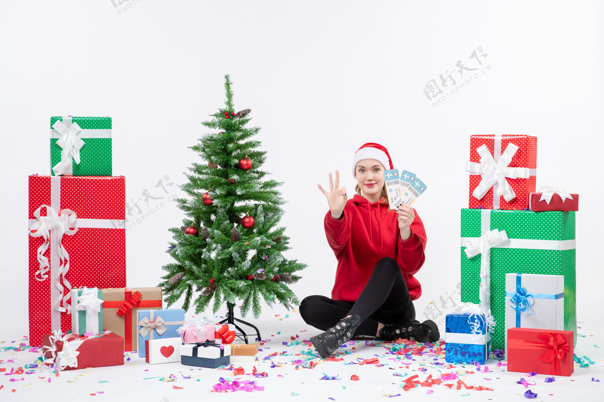 礼物前视图年轻女子围坐在白墙上拿着飞机票的礼物前面圣诞快乐周围