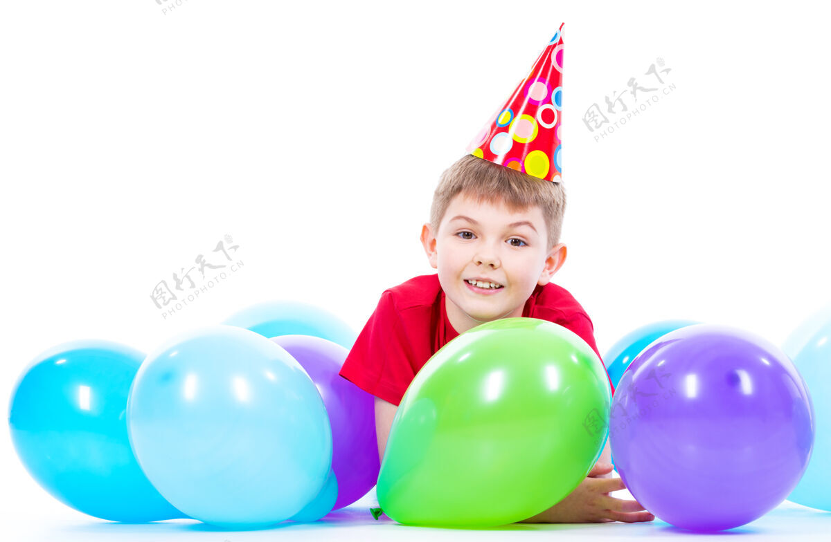 明亮穿着红色t恤的快乐微笑男孩躺在地板上 手里拿着五颜六色的气球——孤立在白色的地板上派对五颜六色T恤