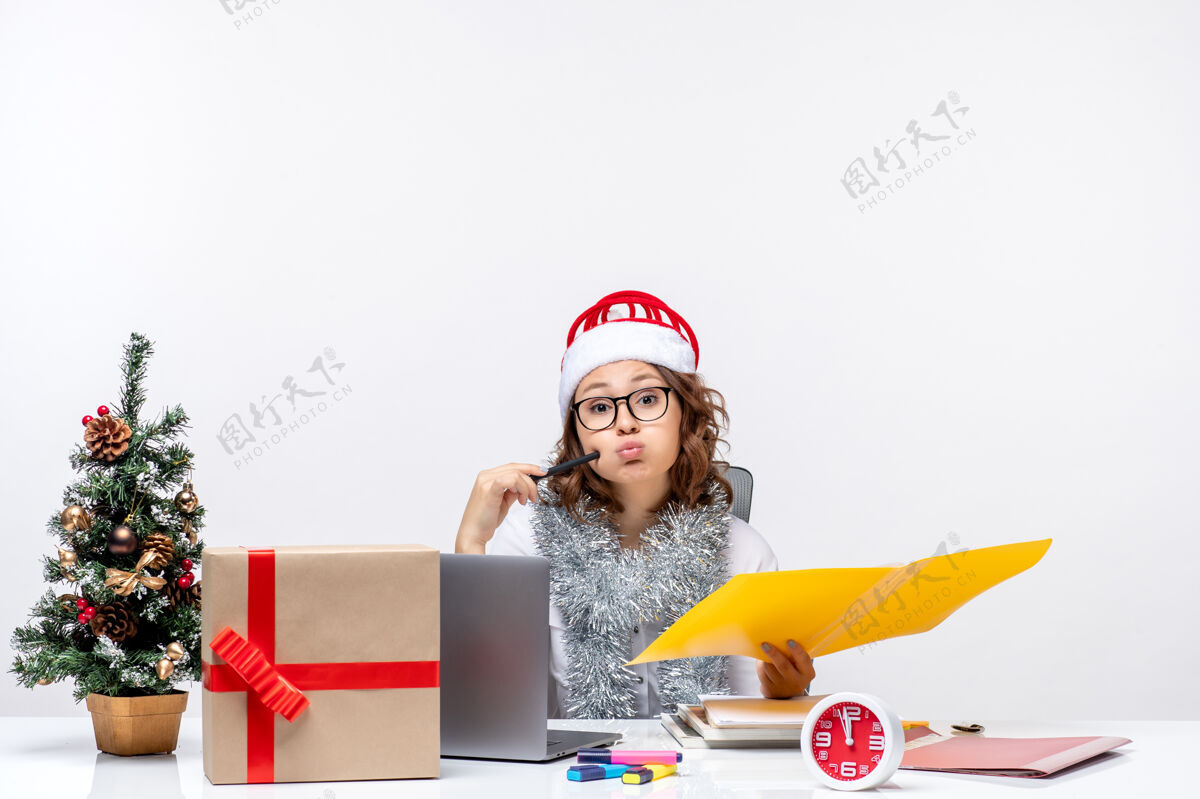 查看正面图：年轻的女工坐在自己的位置前 在白色的办公桌上处理文件办公室文件电脑