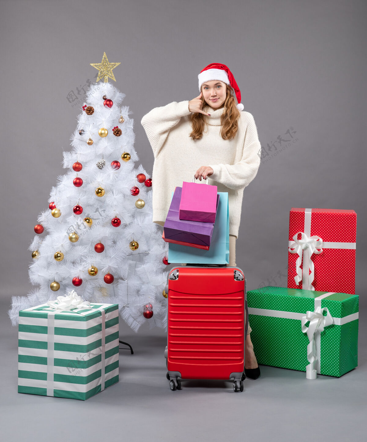 红色正面是金发女孩 戴着圣诞帽 手里拿着红色的手提箱和购物袋 上面有“给我打电话”的牌子帽子年轻圣诞树
