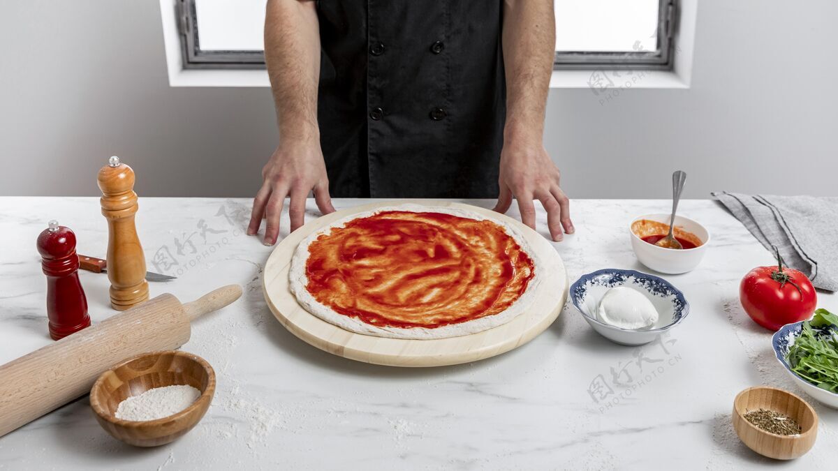 食品高角度的男人在比萨饼面团上涂番茄酱面粉晚餐配料