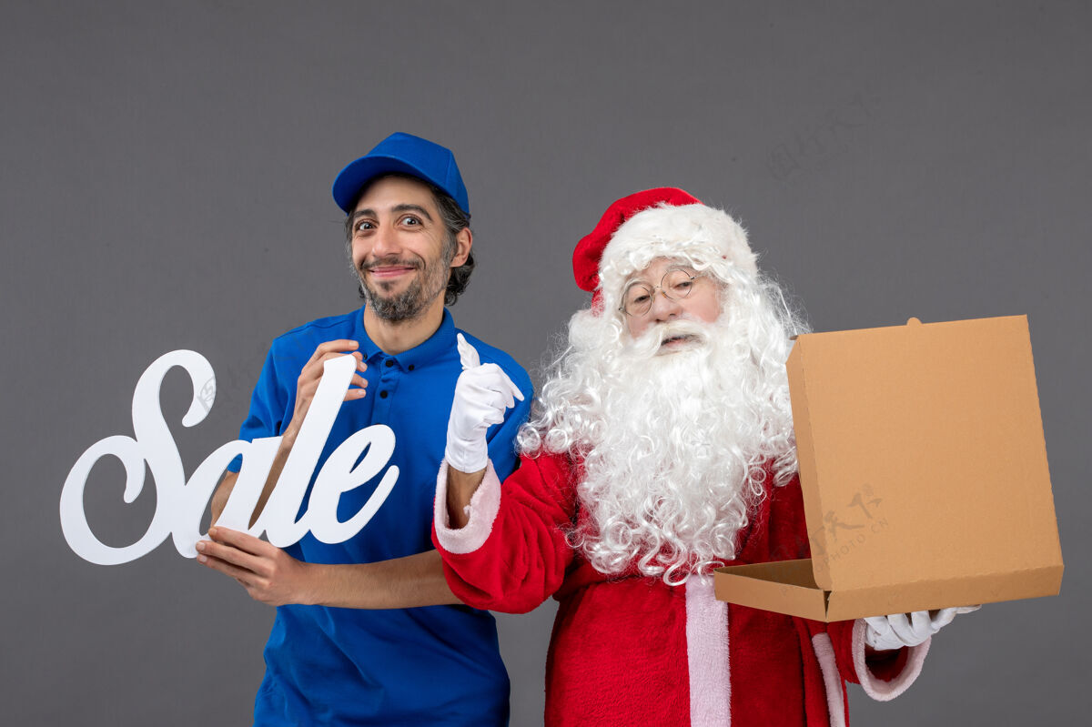圣诞老人圣诞老人的正面图 男信使拿着卖东西的字条 灰色墙上还有空的食品盒快递十二月人
