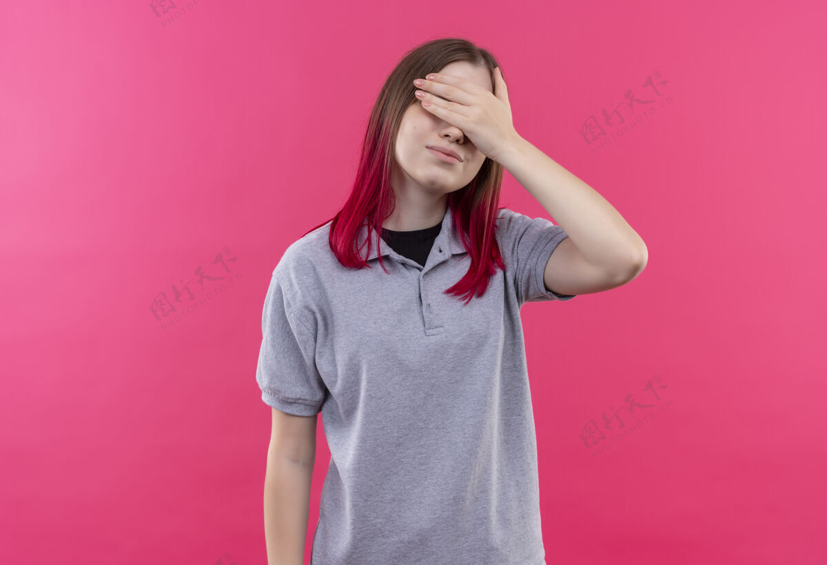 T恤年轻漂亮的女孩穿着灰色t恤 眼睛蒙着 手放在孤立的粉色背景上年轻粉色封面