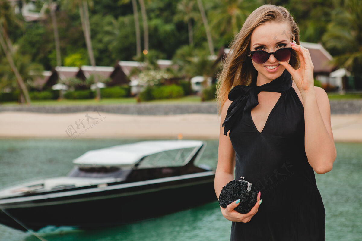 邮轮奢华性感迷人的女人穿着黑色礼服在豪华度假酒店的码头上摆造型 戴着墨镜 暑假 热带海滩年轻模型女人