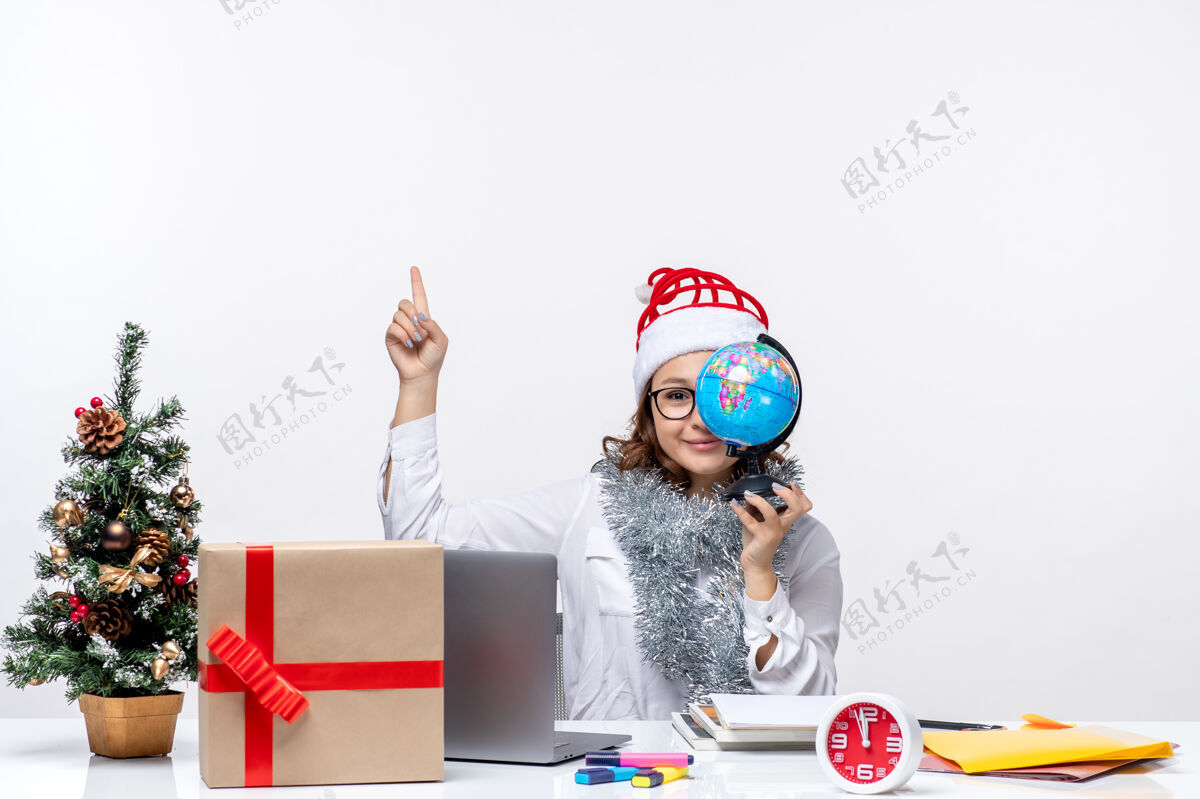 男性正面图：年轻的女工坐在她拿地球仪的地方前面 背景是白色的地球仪抱着圣诞节